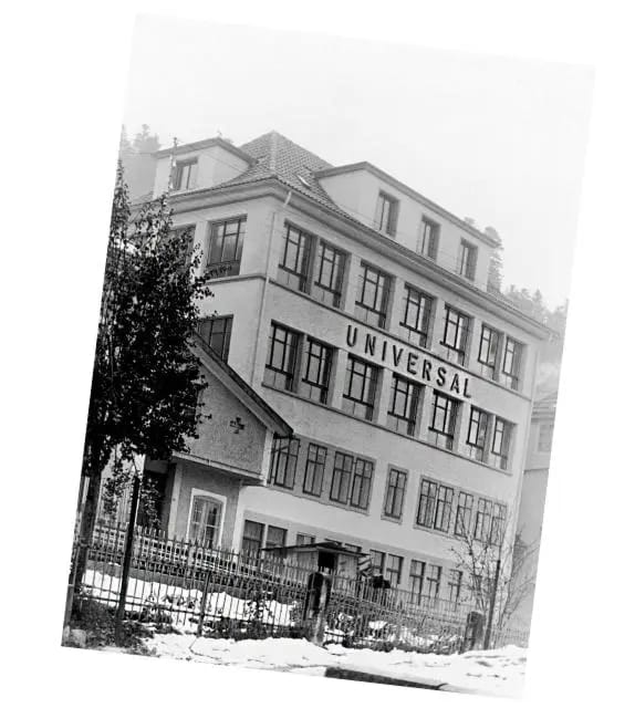 Bâtiment historique Universal Genève en pleine expansion, avec enseigne imposante et décor enneigé d’époque