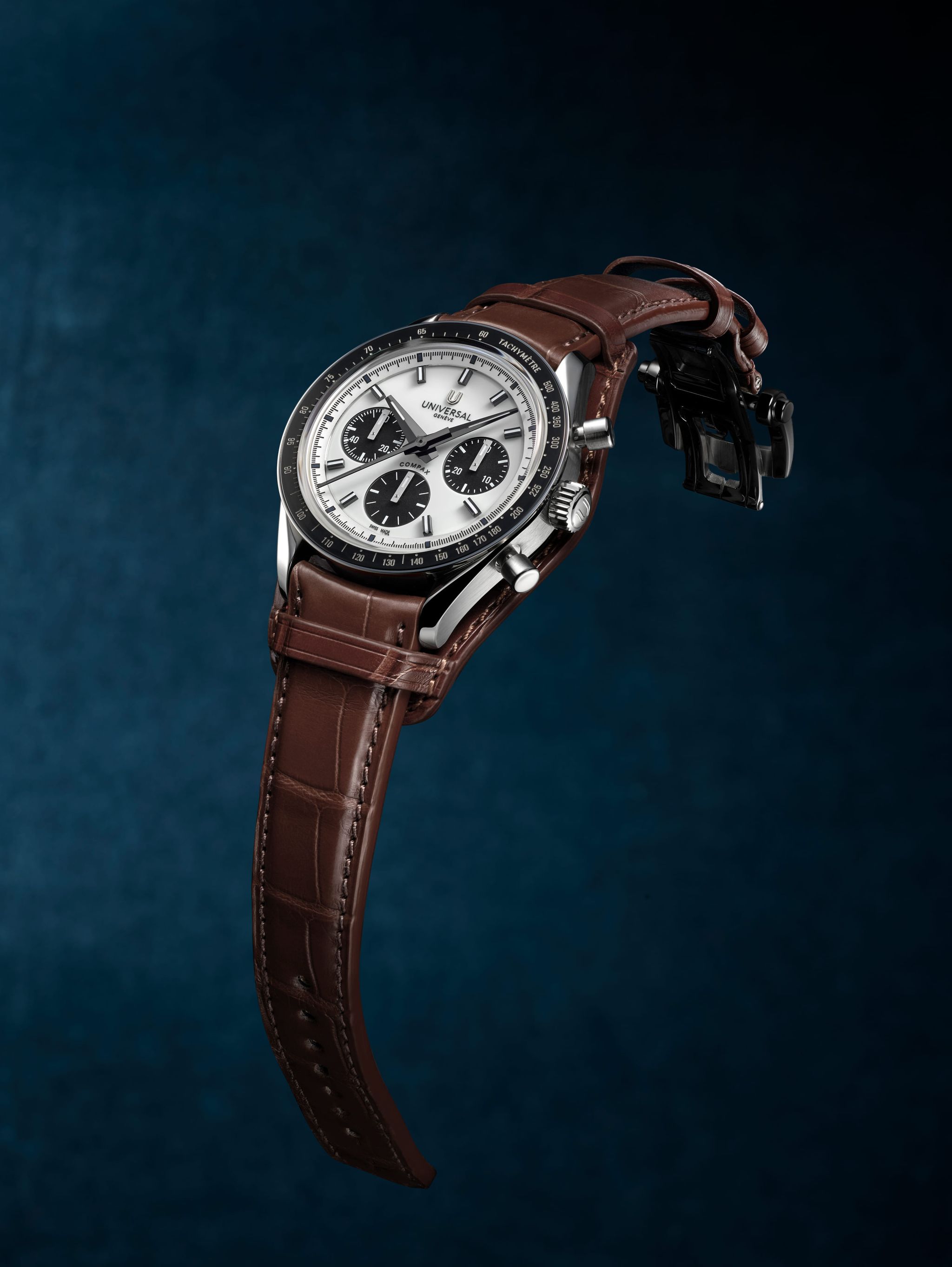 Chronographe Universal Genève Compax à cadran panda blanc et bracelet brun sur fond bleu profond