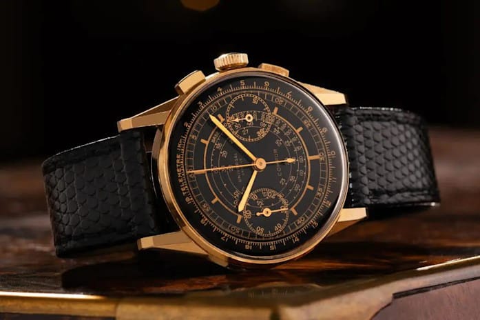 Chronographe Universal Genève au cadran noir et bracelet texturé posé sur un établi d’horloger