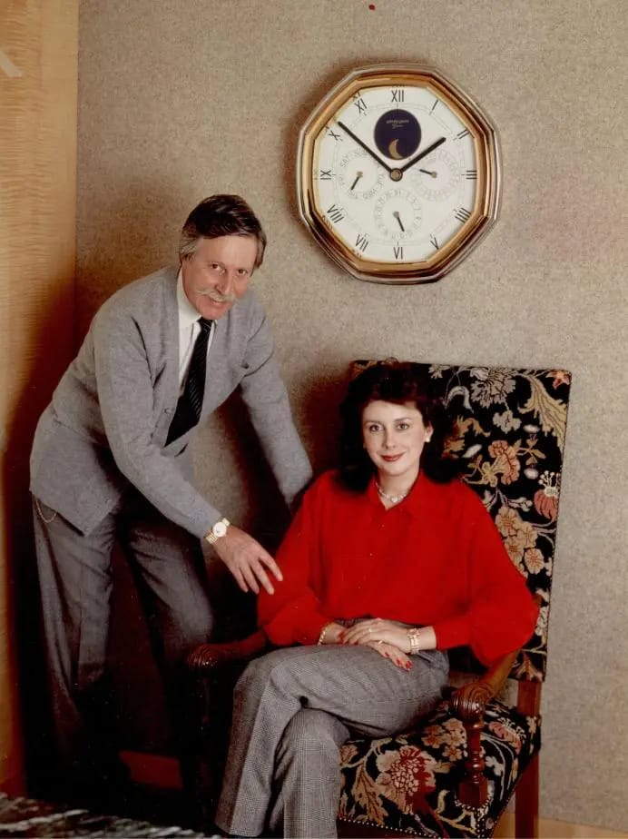 Gérald Genta et une femme assise sous une horloge murale octogonale à phase de lune, décor raffiné