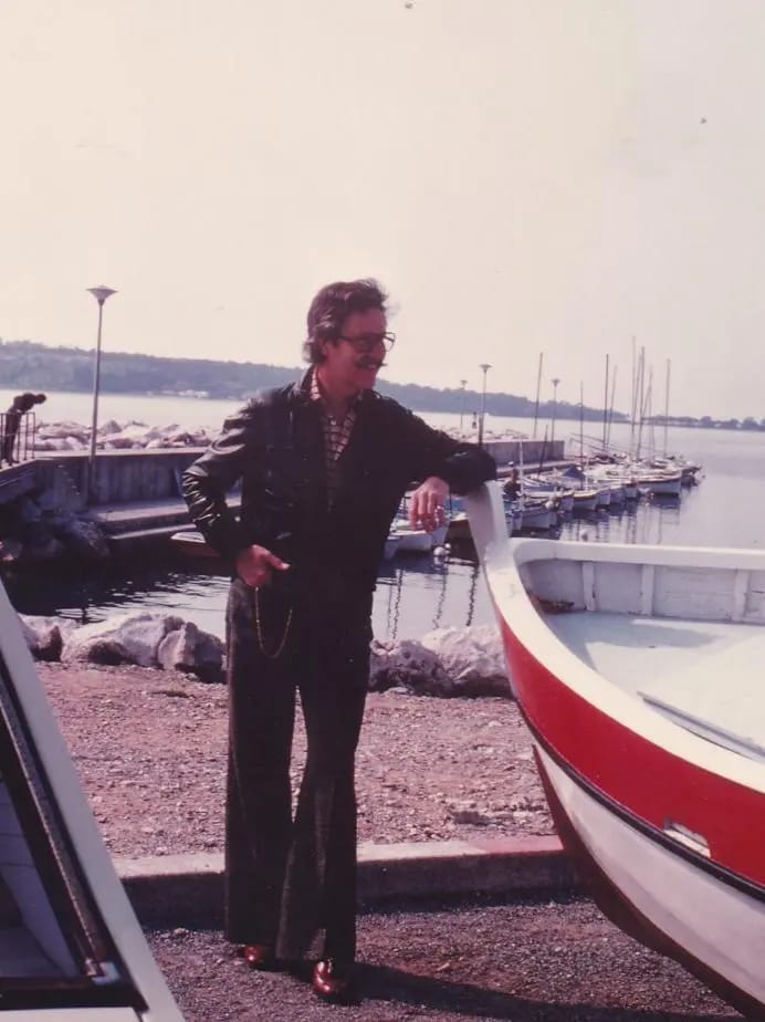 Gerald Genta près d’un bateau rouge dans une marina, présenté dans les archives Universal Genève